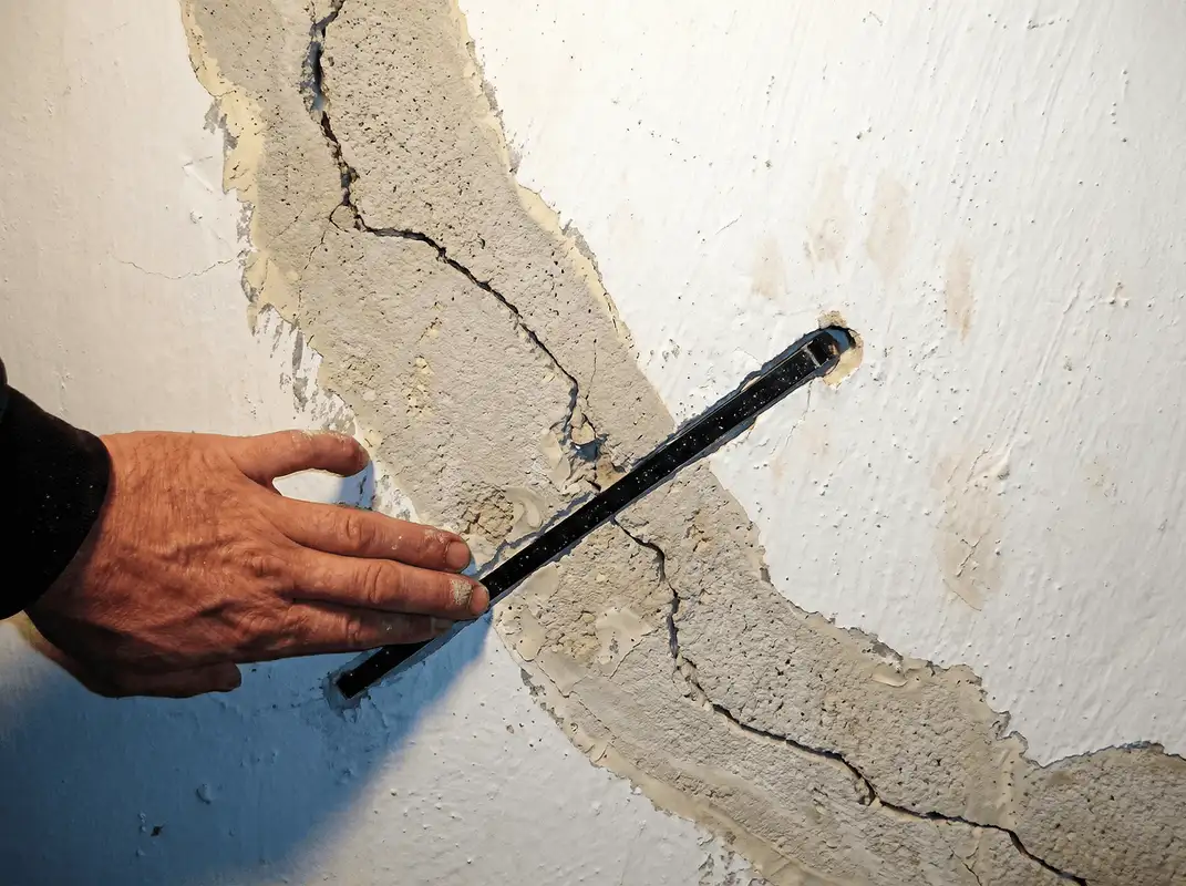 A wall with a large crack is being inspected by a professional in New Orleans, LA